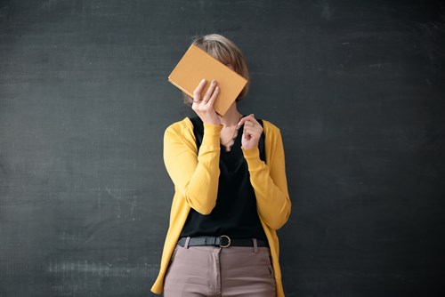 teacher at blackboard hiding face